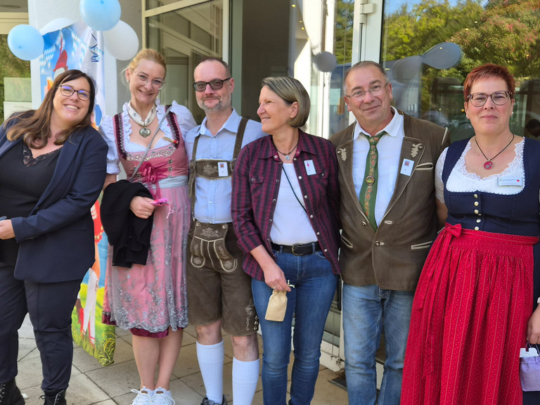 Mitarbeitende stehen zum Teil in bayerischer Tracht vor dem Eingang der Immanuel Klinik Märkische Schweiz 