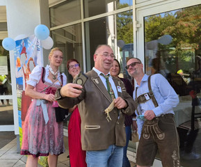 Mitarbeitende stehen zum Teil in bayerischer Tracht vor dem Eingang der Immanuel Klinik Märkische Schweiz 