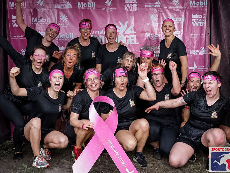 Team der Immanuel Klinik Märkische Schweiz nach dem Muddy Angel Run in Berlin mit pinker Schleife als Zeichen der Solidarität mit Brustkrebspatientinnen.
