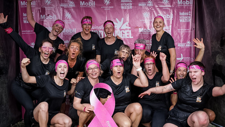 Team der Immanuel Klinik Märkische Schweiz nach dem Muddy Angel Run in Berlin mit pinker Schleife als Zeichen der Solidarität mit Brustkrebspatientinnen.